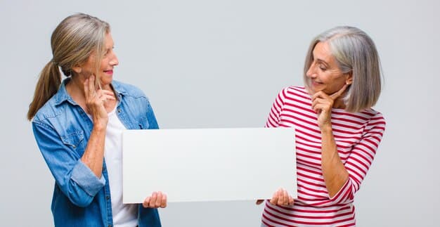 A split screen showing a senior woman on one side and a doctor on the other, both smiling and engaged in a video call. The woman is holding a blood pressure monitor, and the doctor appears to be giving instructions.