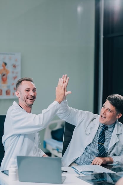 A MedTech startup CEO congratulating a newly hired employee. The CEO and employee are shaking hands with broad smiles, symbolizing a successful onboarding process.
