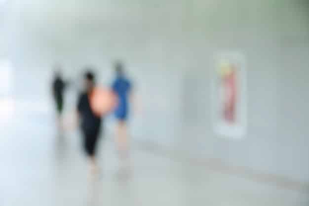 A blurred background of a hospital hallway with medical professionals, overlaid with a digital grid pattern and a prominent green lock icon. The grid and lock symbolize the need for cybersecurity in healthcare.