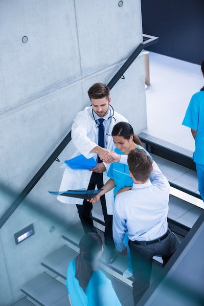 A boardroom scene depicting executives from a MedTech startup and a larger healthcare organization shaking hands, signifying a successful partnership agreement.